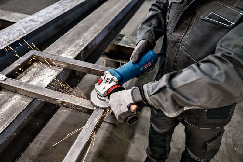 En person som bär säkerhetsutrustning slipar metallbalkar, vilket producerar gnistor.