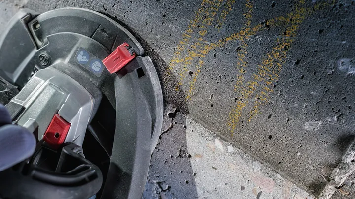 En person med säkerhetsutrustning använder en cirkelsåg för att såga en betongyta.