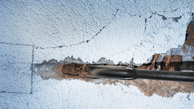 Mejselverktyg som bryter igenom gips på en vägg.