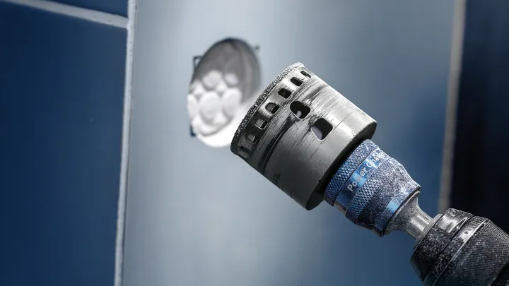 Hålsågstillsats borrar en cirkulär öppning i en blå panel.