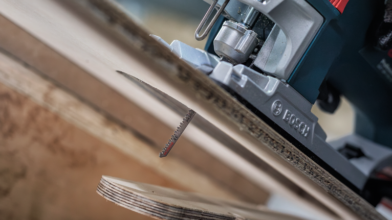 Sticksåg sågar igenom en plywoodskiva.