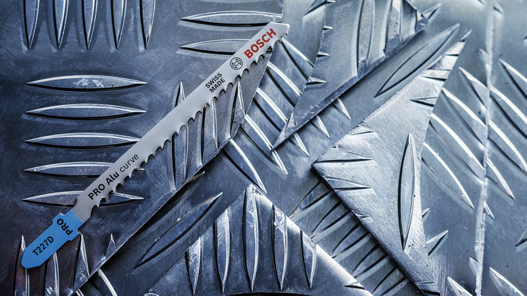 Sågblad vilar på texturerade metallplåtar.