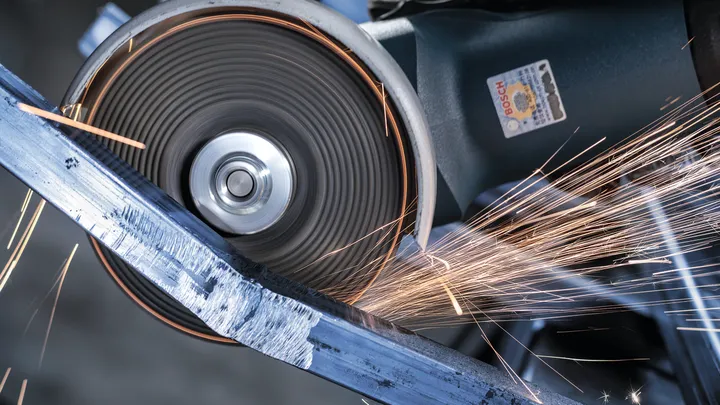 Skärhjul skär genom en metallbalk och producerar ljusa gnistor.