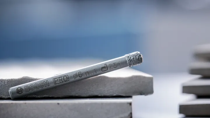 Metallborrspets vilar på staplade keramiska plattor.