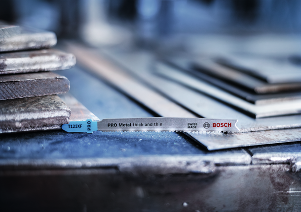 Sticksågblad placerat på staplade metallplåtar i en verkstad.