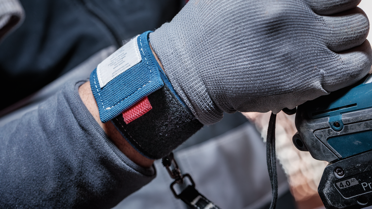 En person som bär säkerhetsutrustning använder ett elverktyg.