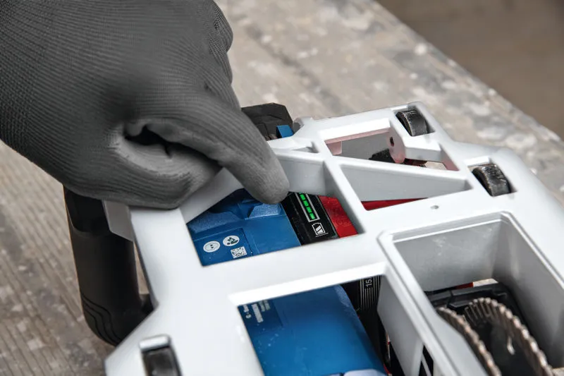 Person som bär säkerhetsutrustning justerar batteriet på en väggfräs.