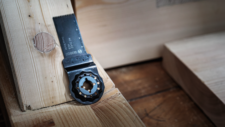 Det oscillerande sågbladet vilar på en träyta bredvid nysågat trä.