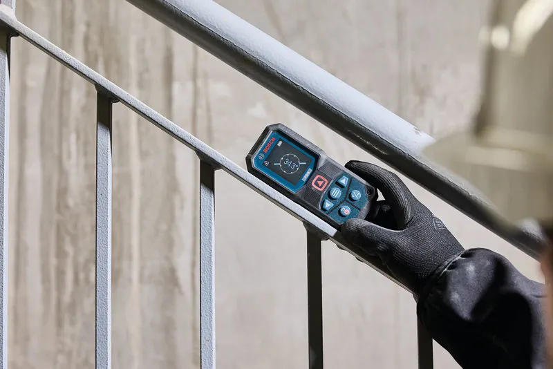 En person som bär säkerhetsutrustning använder en lasermätare för att kontrollera trappans vinkel.