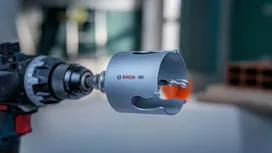 En borrmaskin utrustad med ett hålsågsbits är klar för användning inomhus.