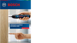 Črna Bosch Professional vrtalna naprava v roki ob leseni površini.