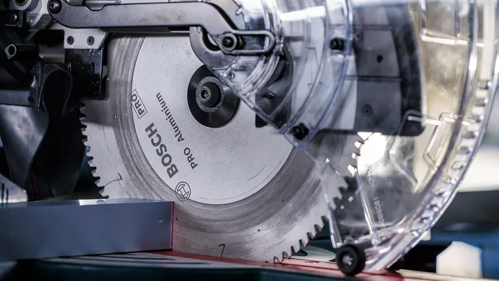 Krožna žaga reže kovinski kos v delavnici.