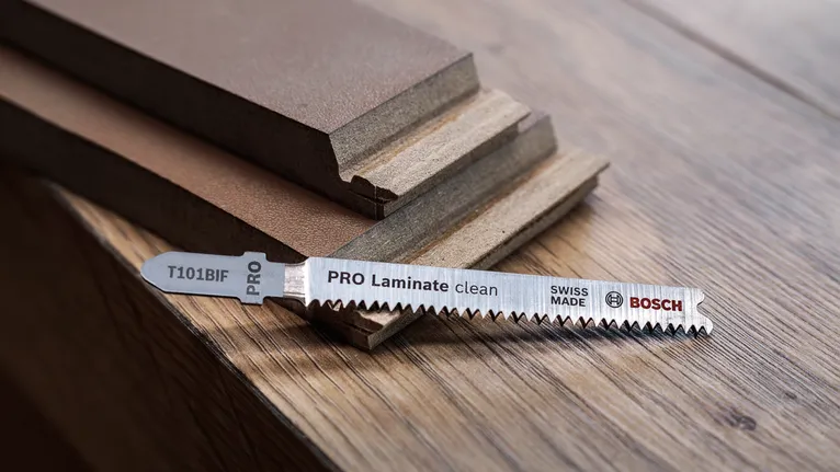 List vbodne žage leži na leseni površini poleg zloženih laminatnih plošč.