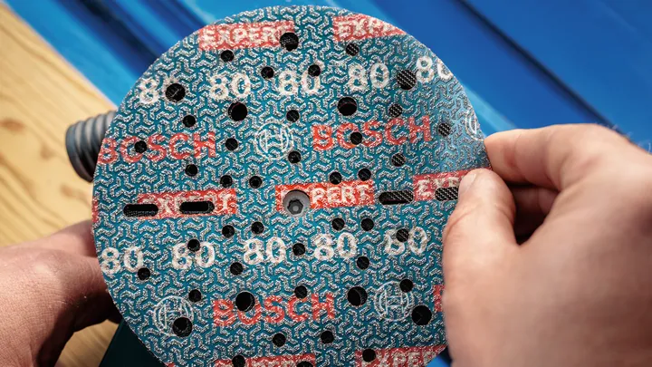 Oseba, ki namešča brusilni disk na električni brusilnik.