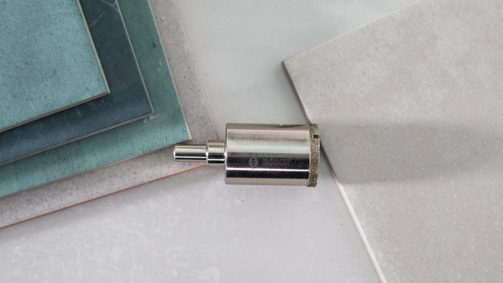 Diamantna luknjača postavljena poleg več keramičnih ploščic.