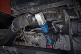 Oseba, ki nosi varnostno opremo, uporablja akumulatorski udarni ključ na težkih strojih.