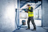 Delavec v varnostni opremi vrta v beton z akumulatorskim vrtalnim kladivom.