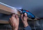 Oseba spajka žične povezave na LED luči z brezžičnim spajkalnikom.