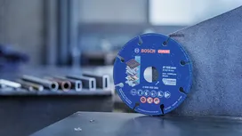 Diamantna rezalna plošča, naslonjena na kovinsko pločevino v industrijski delavnici.