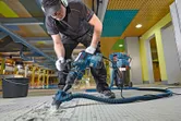 Osoba v bezpečnostnom vybavení obsluhuje demolačné kladivo na rozbíjanie dlažby.