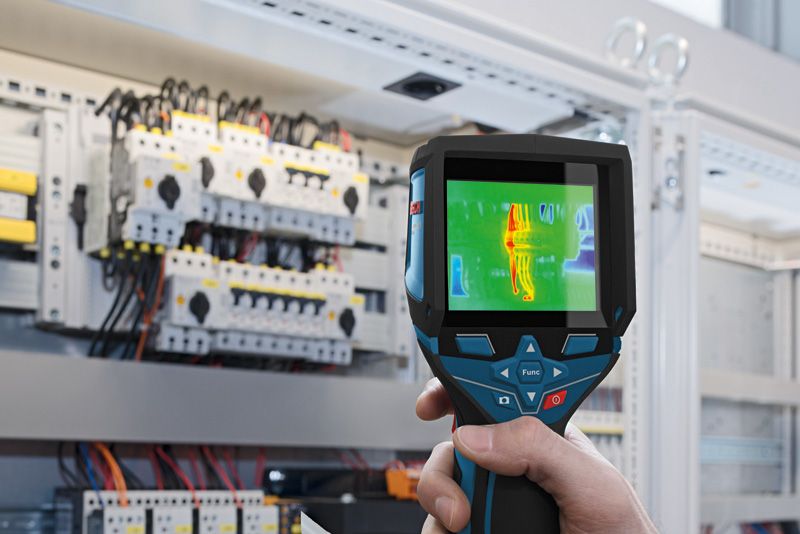 Osoba používa termokameru na kontrolu elektrických komponentov v ovládacom paneli.
