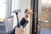 Osoba používajúca kladivo a skrutkovač na inštaláciu mechanizmu zámku dverí.