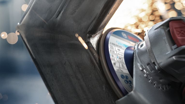 Uhlová brúska reže kov, z miesta kontaktu lietajú iskry.