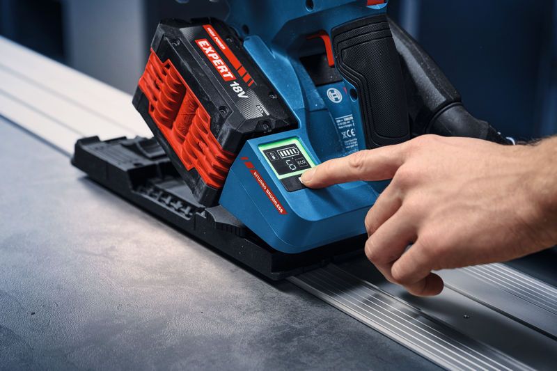 Osoba aktivuje akumulátorovú ponornú pílu na vodiacej koľajnici a kontroluje stav batérie.