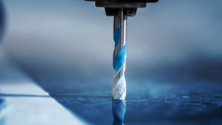 Drill bit boring into a smooth tile surface.
