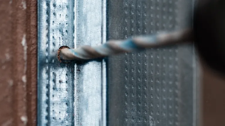 Drill bit creating a hole in a metal surface.