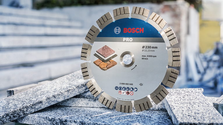 Segmented diamond saw blade resting on granite slabs at a construction site.