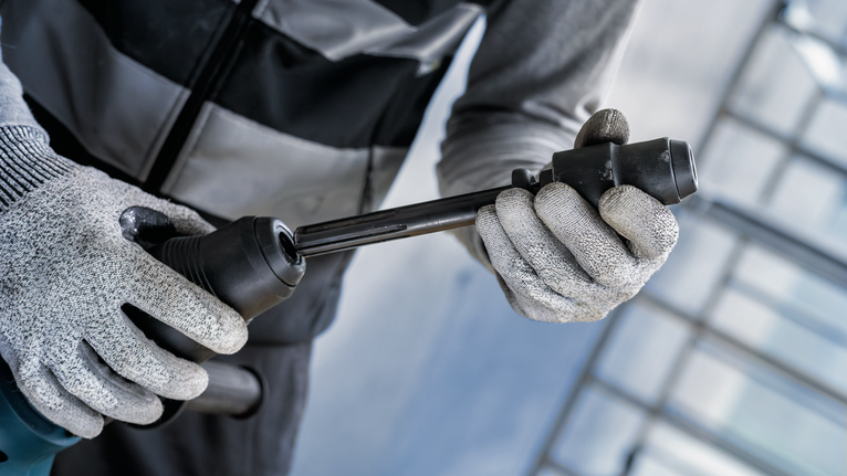 Worker wearing safety equipment inserts a chisel bit into a rotary hammer.