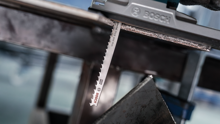 Reciprocating saw blade cutting through a metal sheet.