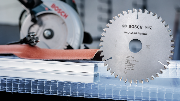 Circular saw blade placed beside a power saw and construction materials.