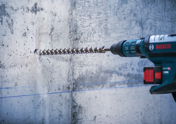 Rotary hammer drilling into a concrete wall.