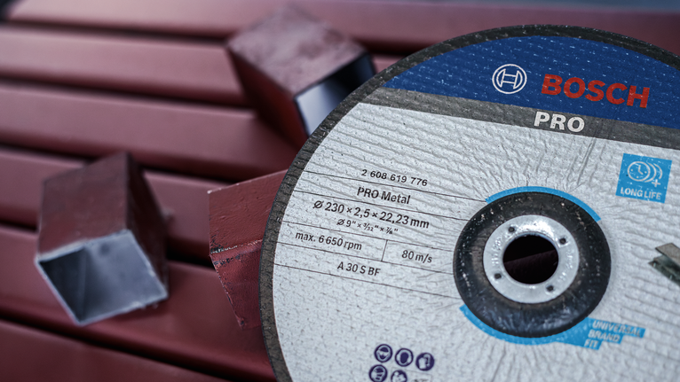 Cutting disc rests on red metal pipes and hollow square metal tubes.