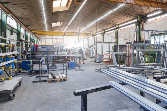 Un ouvrier portant un équipement de sécurité se déplace dans un atelier de fabrication de métaux.