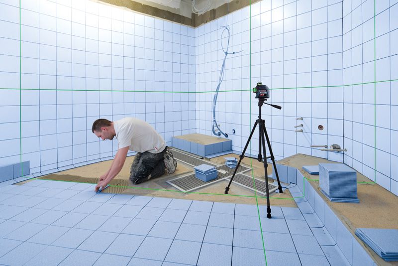 Un homme installe des carreaux de salle de bain.
