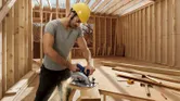 Homme sciant une construction en bois.