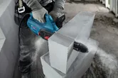 Une personne portant un équipement de sécurité utilise un coupe-bloc AAC pour couper un bloc de béton.