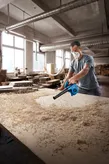 Souffleur Bosch GBL 650 éliminant la sciure d'un établi.