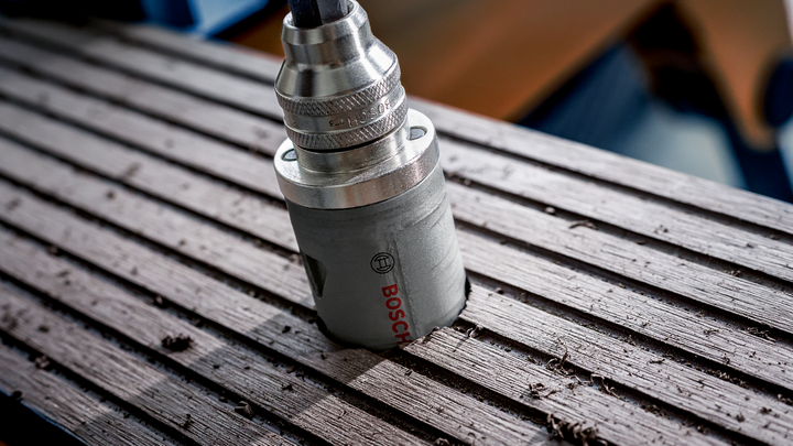 Scie cloche effectuant une coupe circulaire dans une surface en bois.