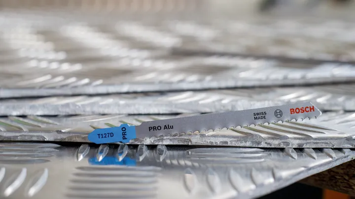 Lame de scie reposant sur des feuilles empilées de métal texturé.