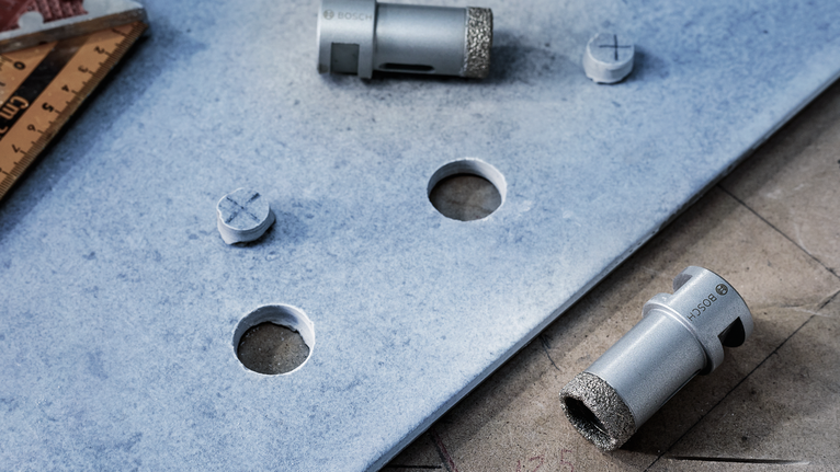 Scies cloches diamantées placées sur une tuile avec des trous circulaires fraîchement percés.
