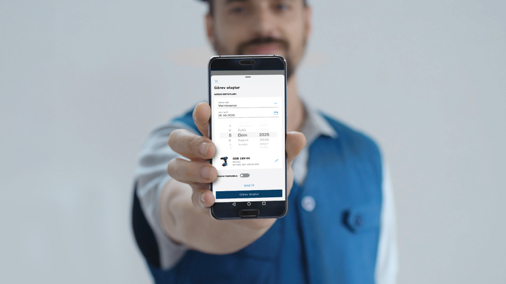 Bir adam, elindeki akıllı telefonla görev oluşturma ekranını gösteriyor.