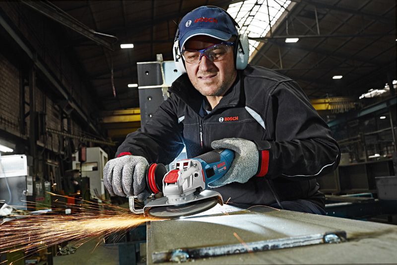 Güvenlik ekipmanı takmış bir kişi açılı taşlama makinesiyle metal öğütüyor, kıvılcımlar çıkıyor.