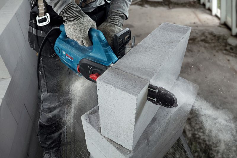 Güvenlik ekipmanı takan bir kişi, beton bir bloğu kesmek için AAC blok kesici kullanıyor.