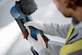 Güvenlik ekipmanı takan bir kişi, bir şantiyede akülü beton çivi çakma makinesini ayarlıyor.