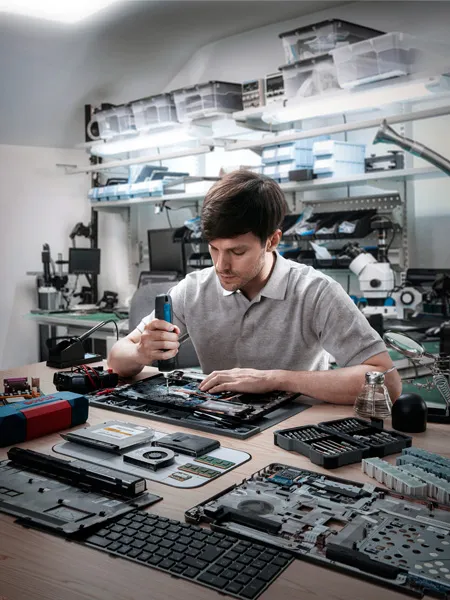 Atölyede kablosuz tornavida ile elektronik cihazları monte eden kişi.