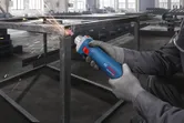 Güvenlik ekipmanı takan bir kişi, metal bir çerçeveyi düzeltmek için düz bir taşlama makinesi kullanıyor.